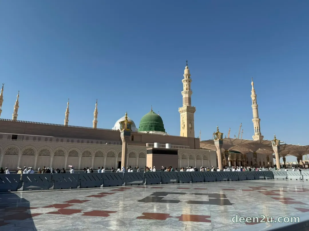 Al-Qubbah al-Khadra, the Green Dome, rising above Masjid an-Nabawi's courtyard in Madinah, with its minarets against a clear sky.