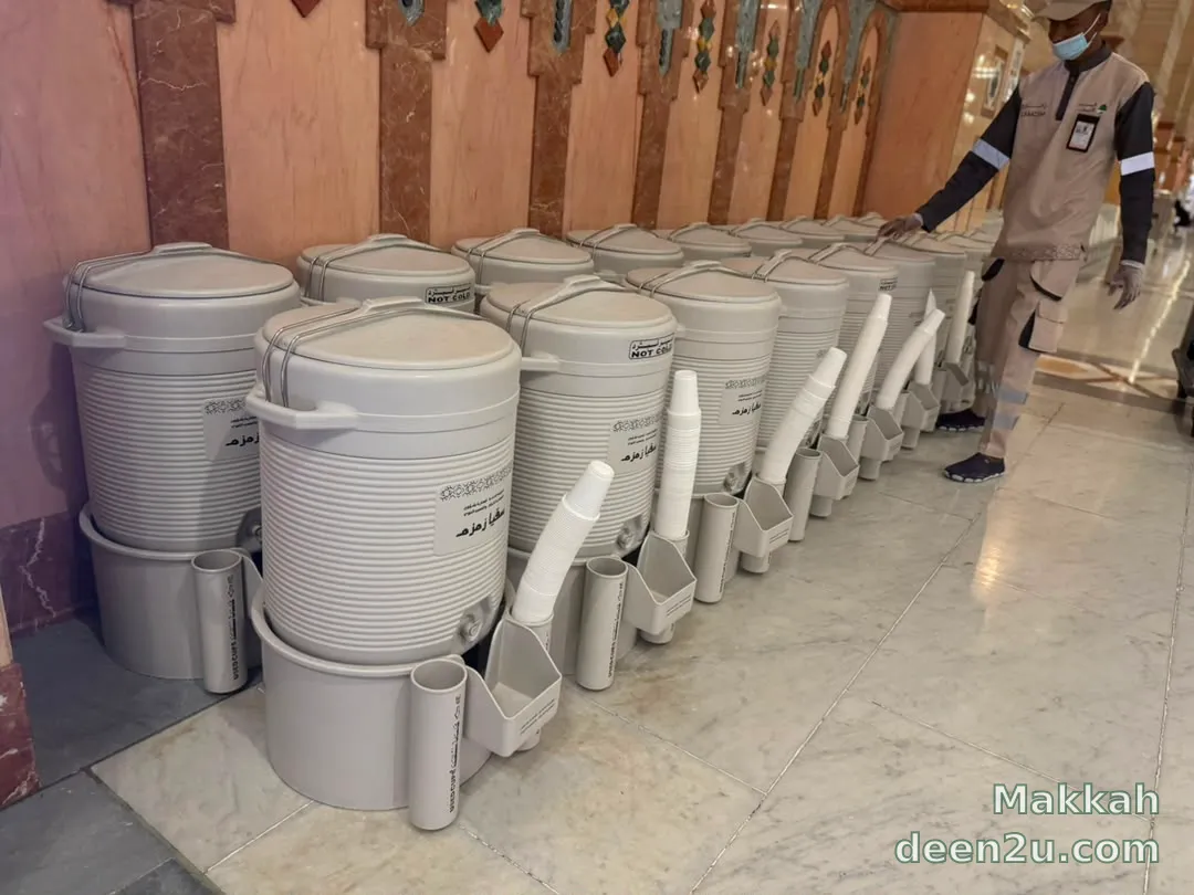 Rows of labelled Zamzam water dispensers with stacked cups inside Masjid al-Haram.